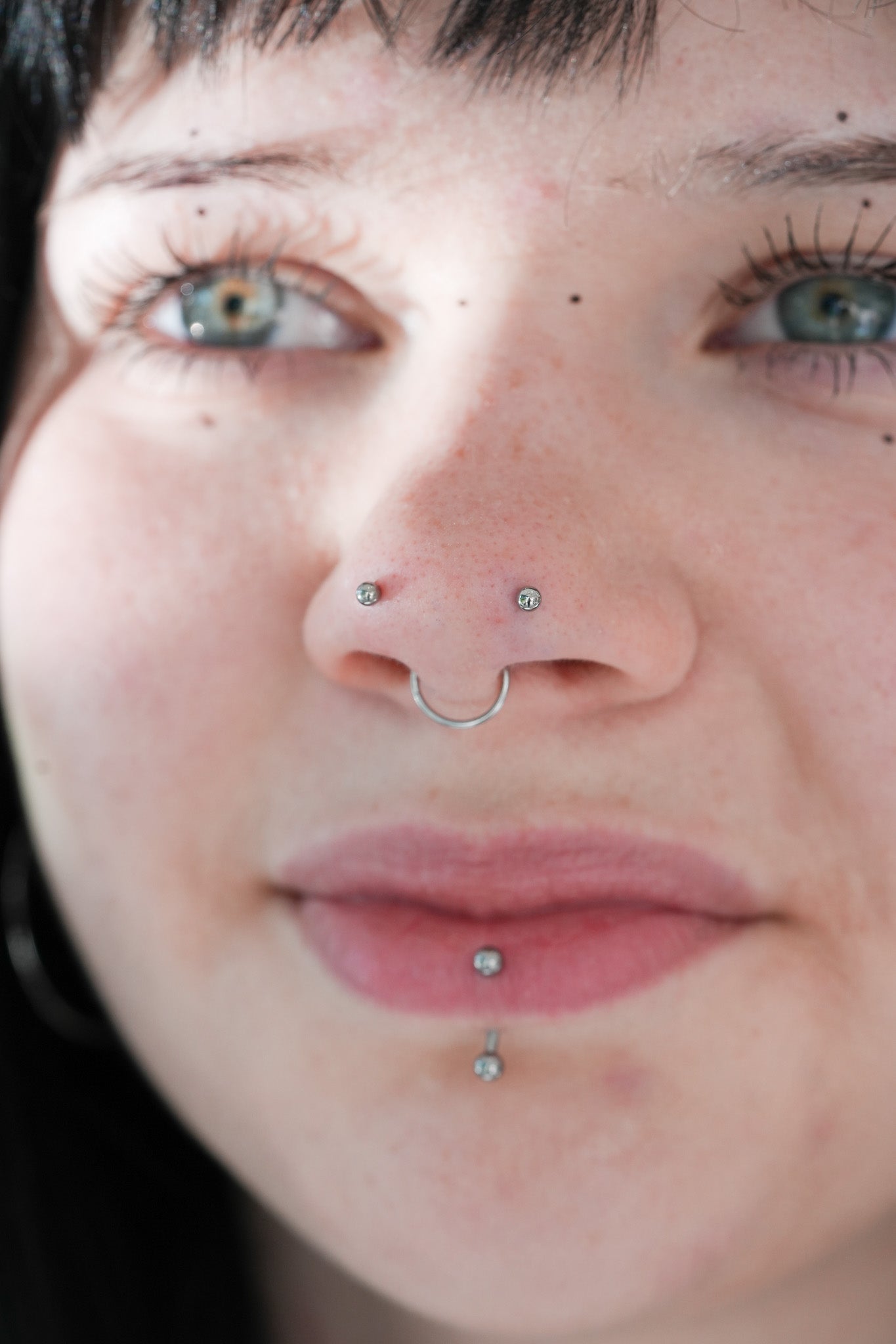 Portret osoby z kolczykami w nosie i ustach – piercing twarzy