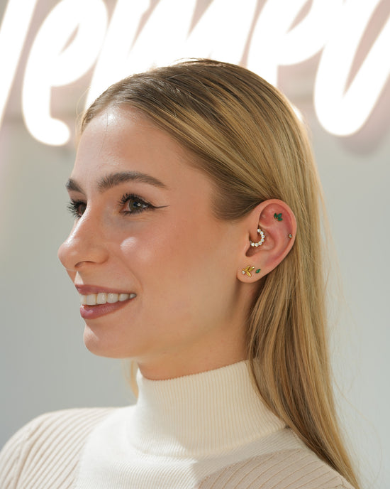 Uśmiechnięta klientka z artystycznie skomponowanymi kolczykami w uchu, podkreślającymi jej styl i charakter