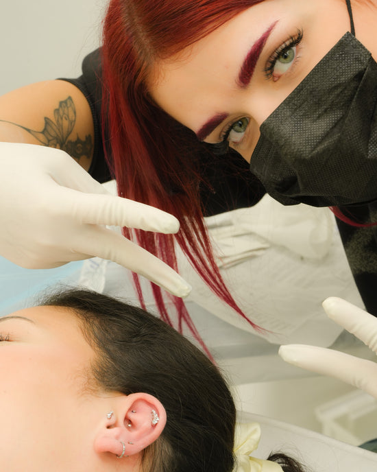 Skoncentrowana piercerka pracująca przy stanowisku zabiegowym w profesjonalnym salonie piercingu