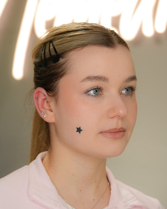 Ucho klientki z przekłuciami typu rook i helix, ozdobionymi harmonijnie dobraną biżuterią