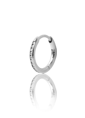 Srebrny kolczyk w kształcie koła z cyrkoniami na jasnym tle